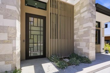 Modern house entrance with geometric glass door and stone walls.