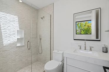 Modern bathroom with glass shower and white fixtures.
