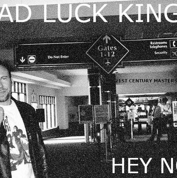 Black and white image of a man in an airport terminal near gate signs.