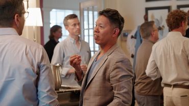 Two men engaged in a conversation at a social gathering indoors.