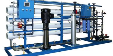 Industrial reverse osmosis water filtration system with blue frame and multiple pipes.