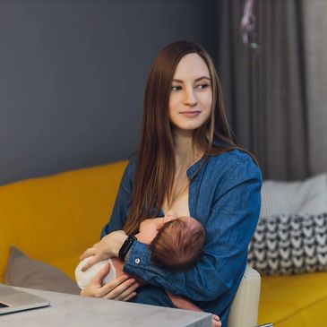 Working mother holding baby while working at home
