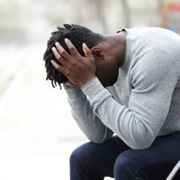 Stressed and depressed black male holding hands on head.