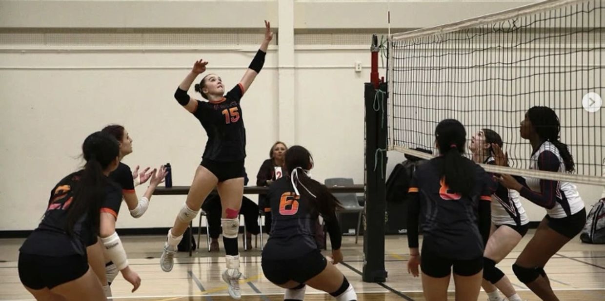 Female volleyball player jumping to spike the ball during a match.