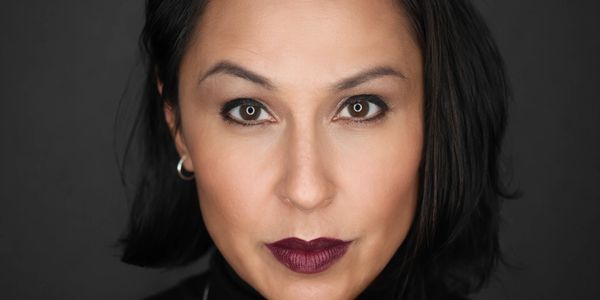 Close-up portrait of a woman with dark hair and bold lipstick.