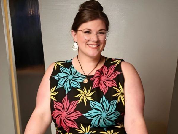 Smiling woman in floral dress with glasses.