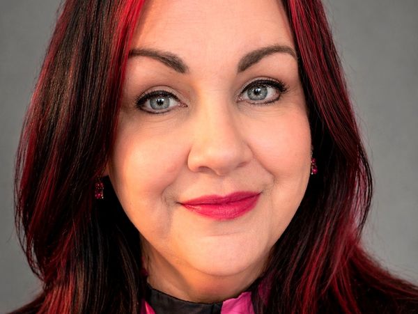 Close-up portrait of a woman with red-highlighted hair and bright makeup.