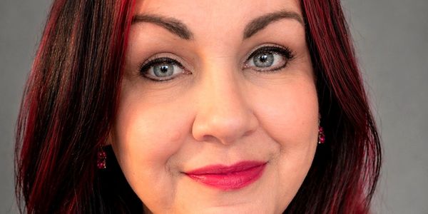 Close-up portrait of a woman with red-highlighted hair and bright makeup.