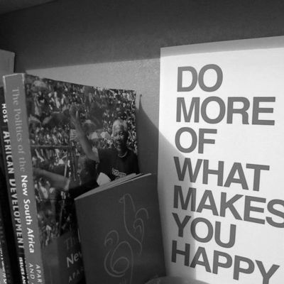 Books about South Africa next to a poster that says, "Do more of what makes you happy."