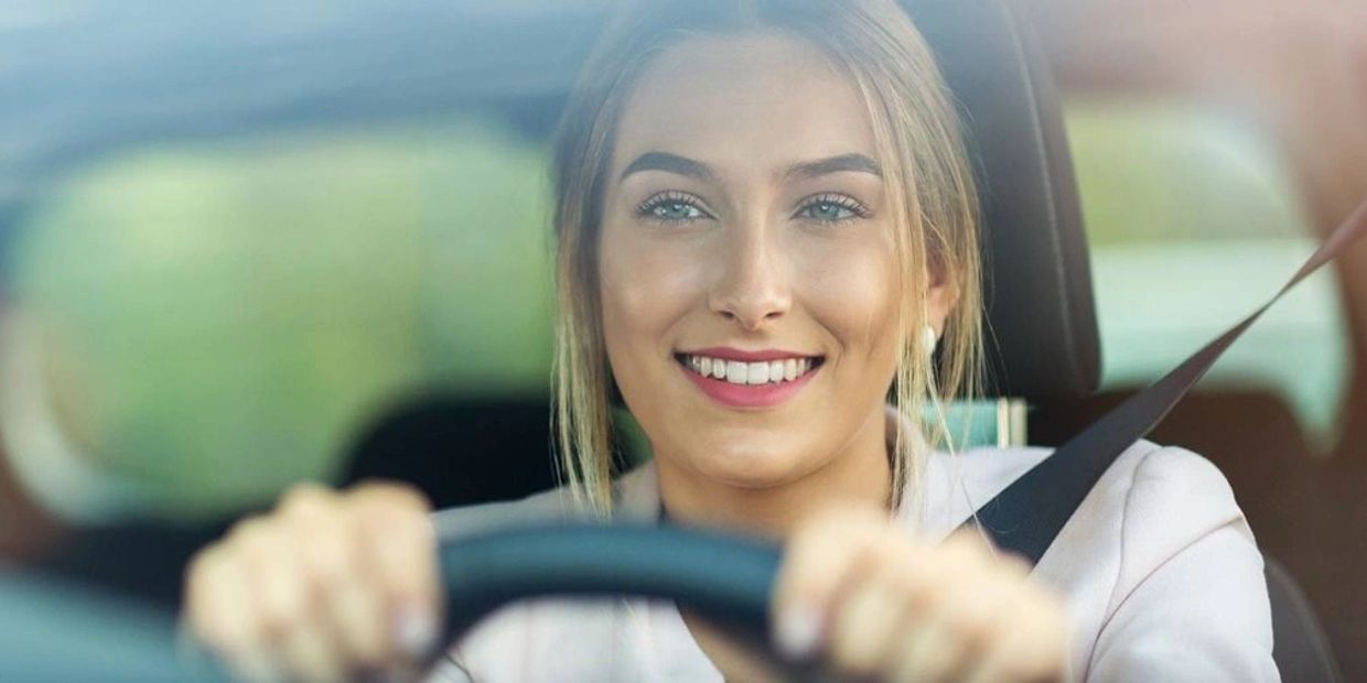 A young happy lady driving her car.