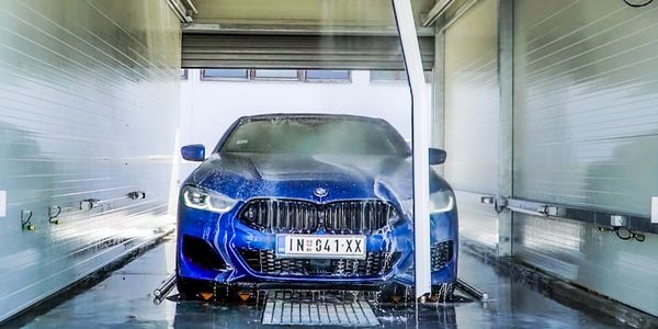 A blue BMW driving through a touchless car wash.