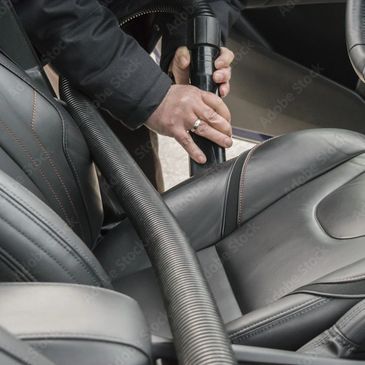 Man vacuuming out car with leather upholstery.