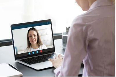 Person video calling a woman on a laptop at a desk.