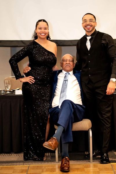 John Lynch seated in a blue suit with family at his 90th birthday