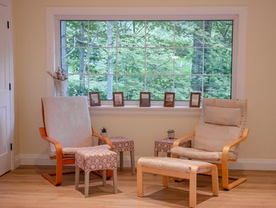 Two chairs in an office with an open window behind and overlooking a forest.