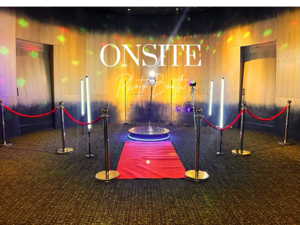 Photo booth setup with red carpet and stanchions.