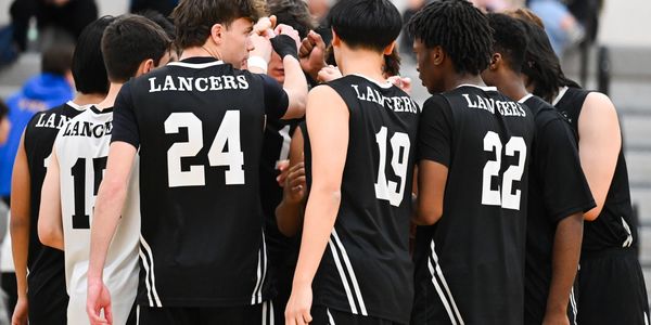 High school basketball players in Lancers jerseys huddle during a game.