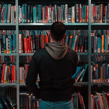 Man looking at a bookshelf in a library