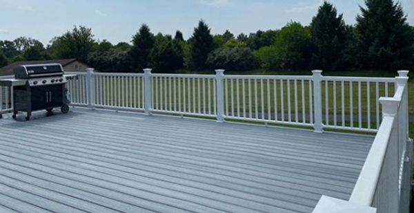 Spacious outdoor deck with white railing and a barbecue grill.