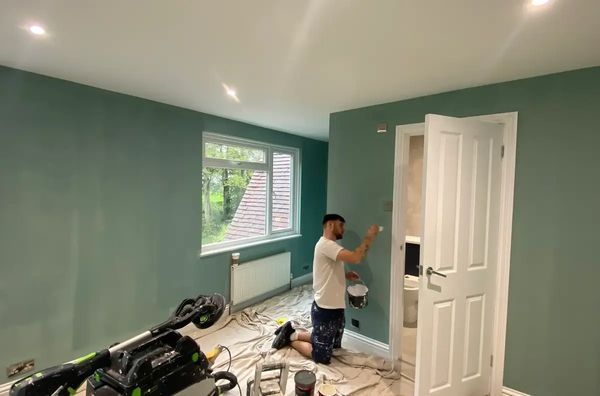 Painter painting the walls green using a good quality brush for a smother finish 