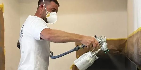 Spray painter spraying paint on a kitchen worktop 