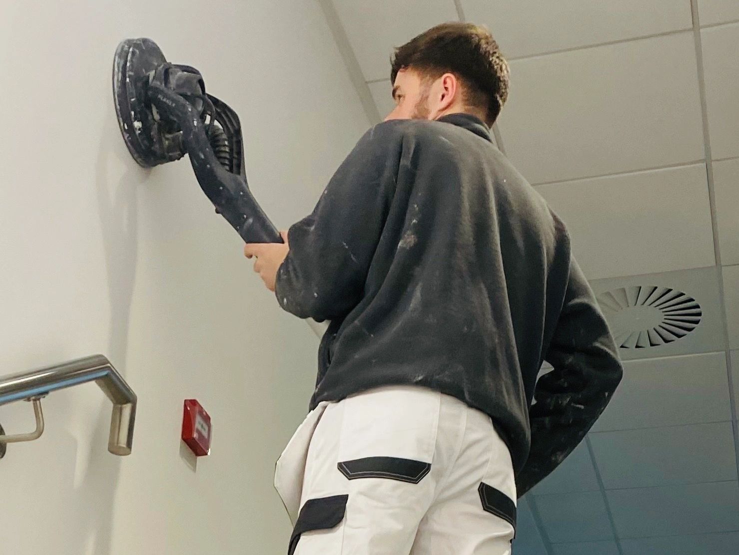 Owner Ryan Smith preparing the surface of an interior wall using a dustless sander 