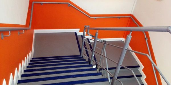 Freshly painted orange and white stairwell in a college building with blue stair treads