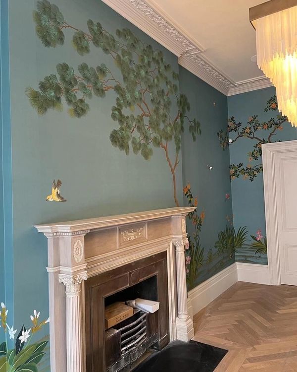 Full room mural wallpaper in a period-style living room with blue-green walls and decorative tree