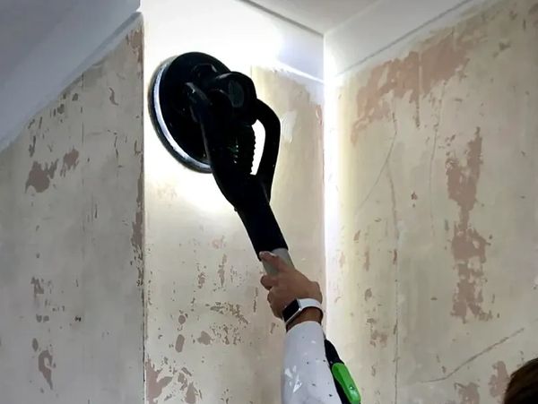 Decorator working on sanding a wall using Festool dust extractor