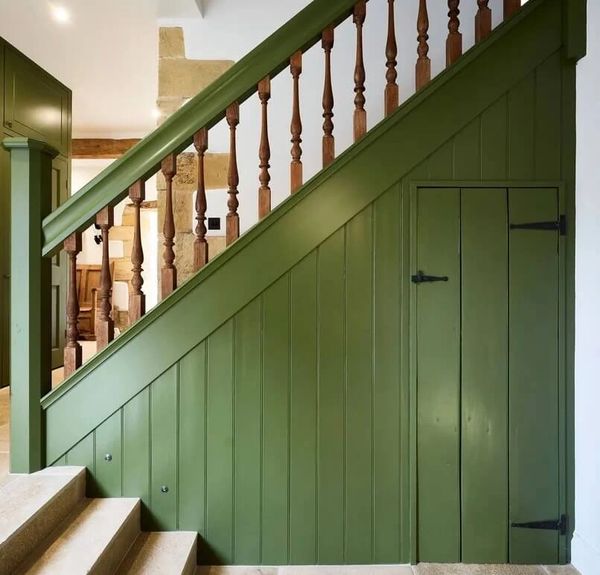 Green painted staircase panelling with under-stairs cupboard, wooden spindles and carpeted steps