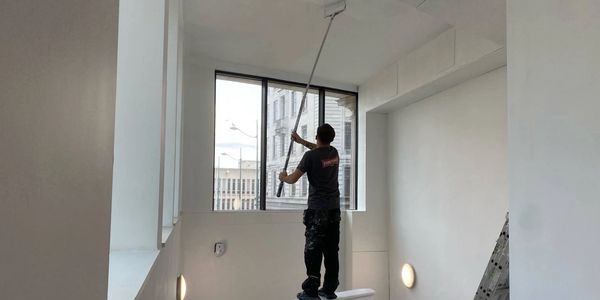 Commercial building interior RH Smith Painting a ceiling using a paint roller on a pole