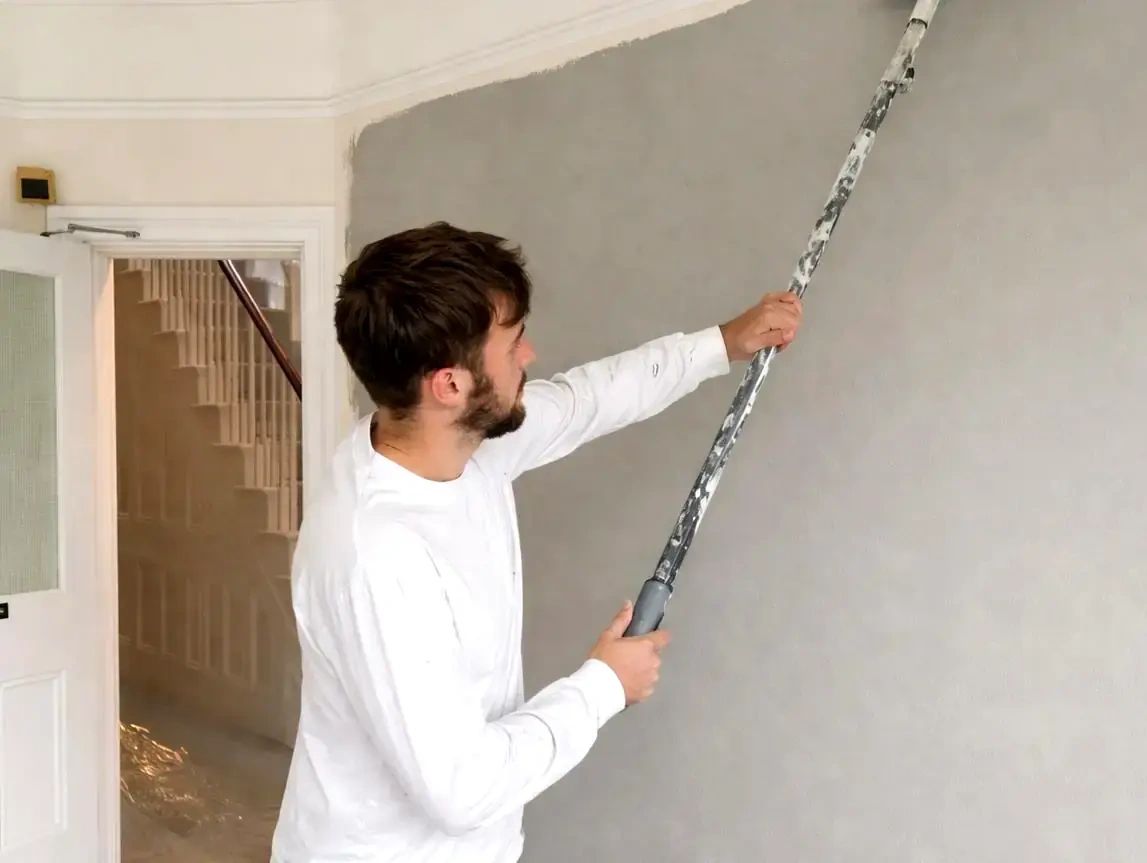 RH Smith painting an interior wall using a paint roller and long pole