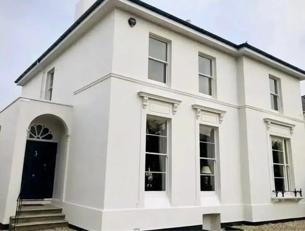 Fresh white exterior house painting with clean rendered walls and black front door.