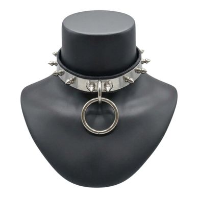 Silver spiked collar with a large ring displayed on a black bust.
