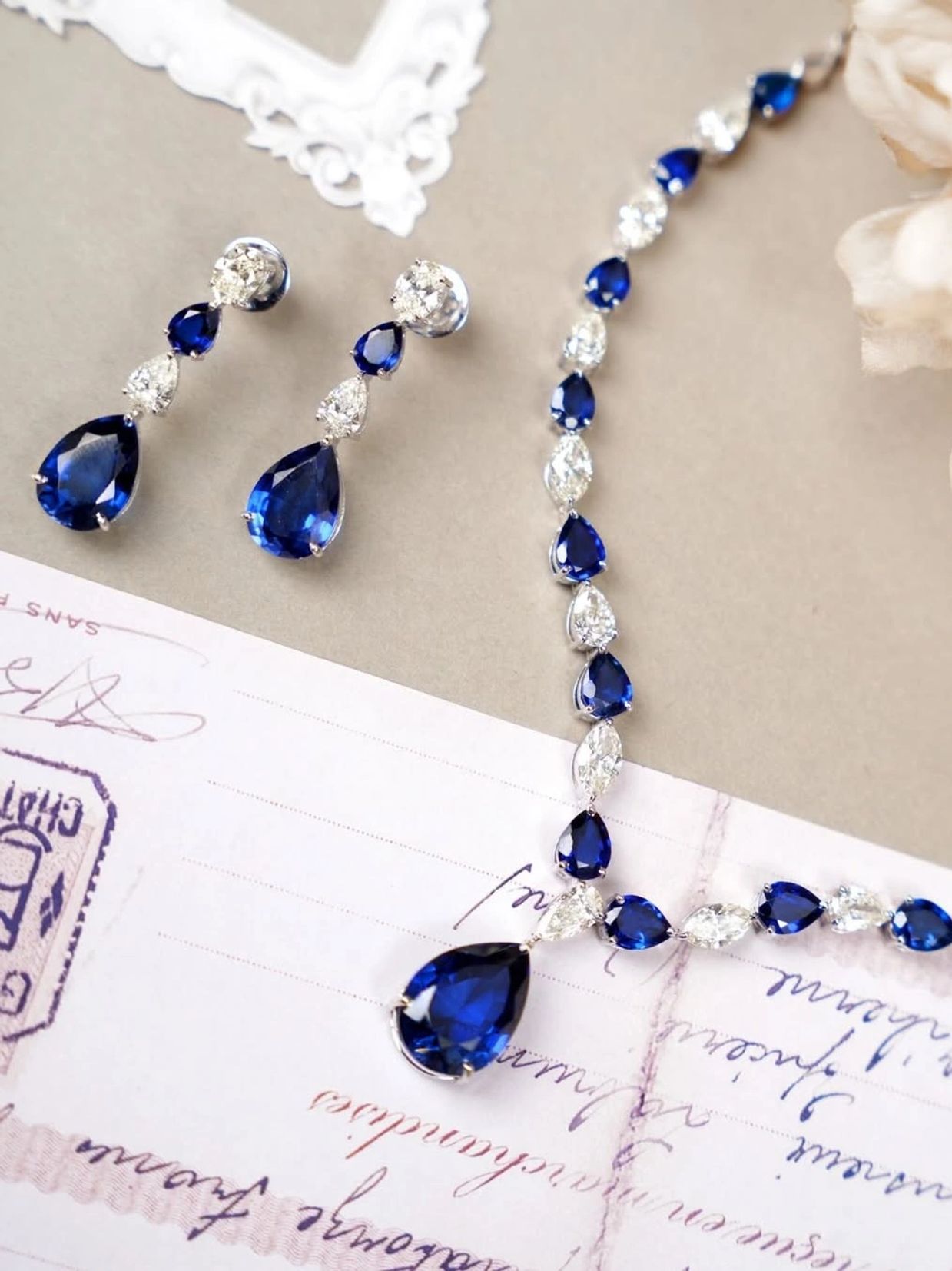 Elegant sapphire and diamond jewelry set on a vintage postcard.