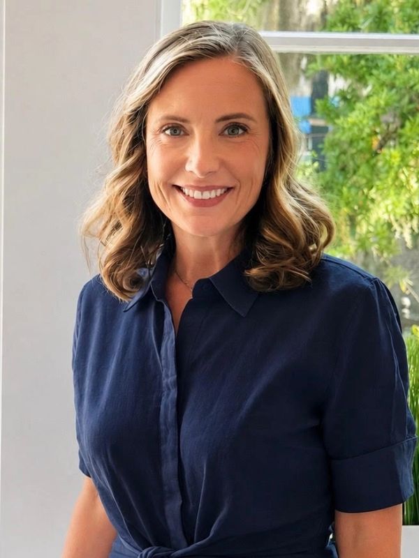 Smiling woman wearing a navy blue shirt.