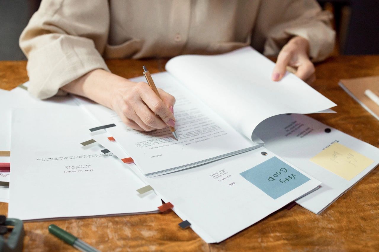 Woman working on a table with documents in front of her.