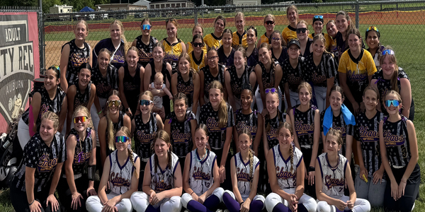 Large group of female softball players posing together on a sunny day.