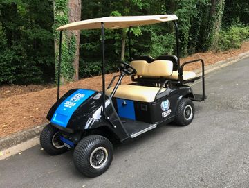A company-branded shuttle cart parked along a tree-lined driveway.