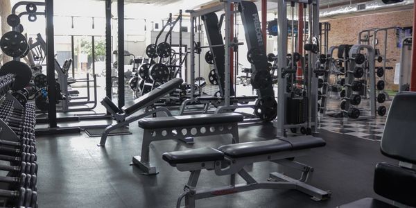 Modern gym with various weightlifting equipment and benches.