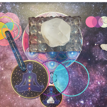 A clear crystal on a textured metallic block with spiritual-themed circular cards and a cosmic background.