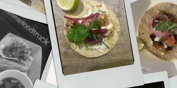 A taco topped with cilantro, pickled onions, and lime wedge on a corn tortilla.