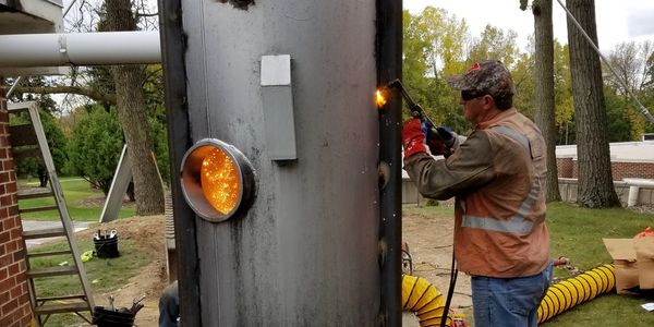 A man welding a large metal structure outdoors.
