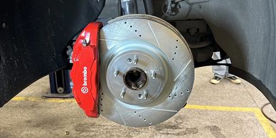 Close-up of a Brembo brake system with drilled rotors on a car wheel hub.