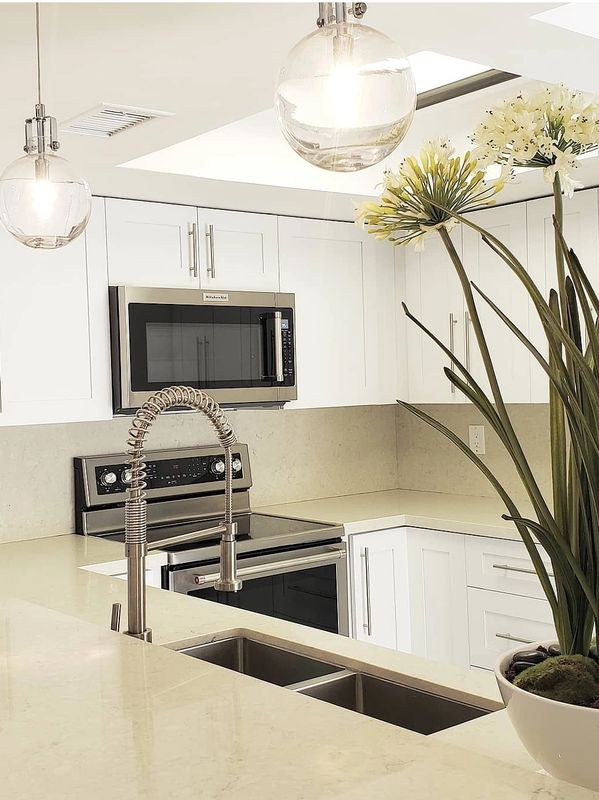 Modern kitchen with white cabinetry, stainless steel appliances, and a floral centerpiece.