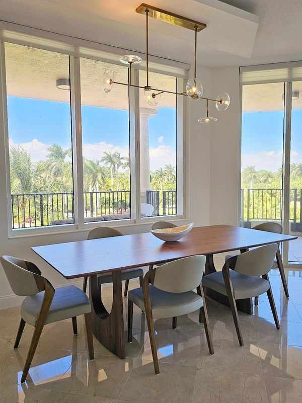 Modern dining area with wooden table and large windows.