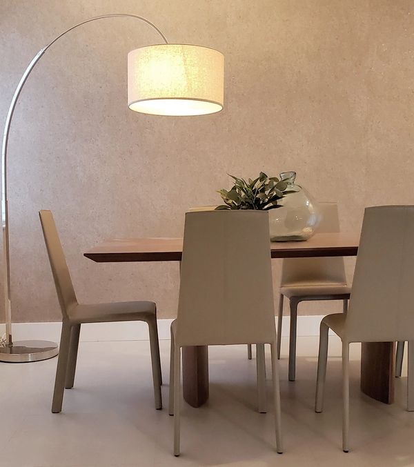 Modern dining area with beige chairs, wooden table, and arc floor lamp.