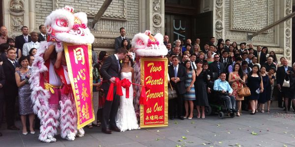 A Chinese wedding with dragons and the entire wedding party standing on the steps of the venue