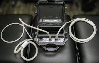 Portable ultrasound machine with probes on a black surface.