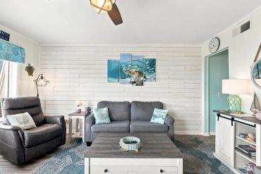 Cozy living room with gray sofa and ocean-themed decor.